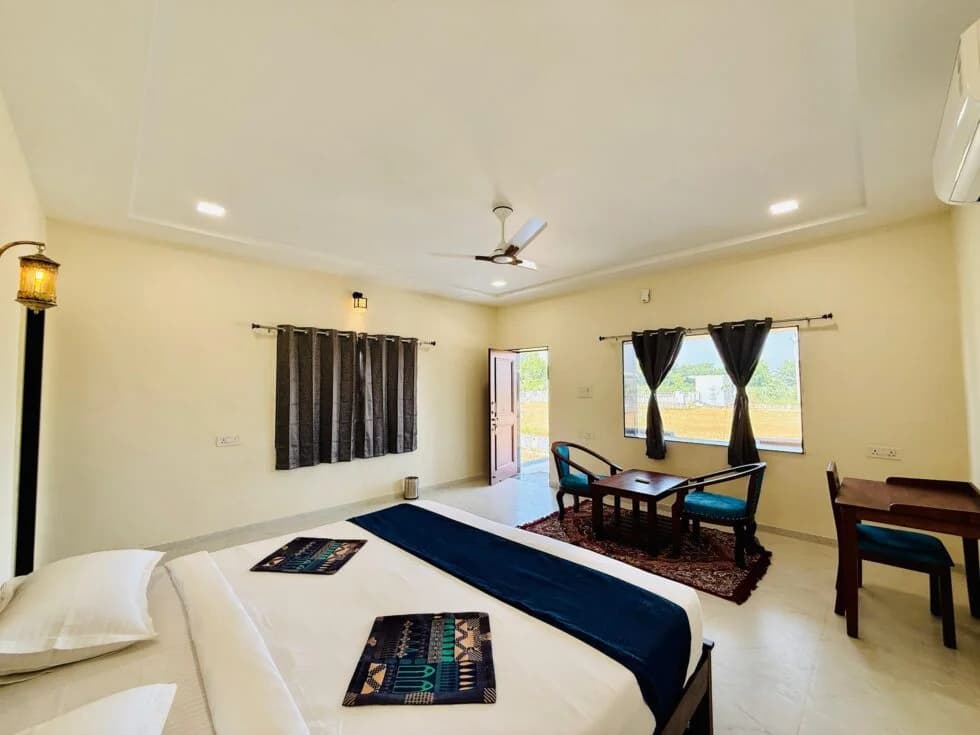 Bright daytime interior of a tented cottage at Upvan Jawai, with a made bed and a doorway open to the grounds