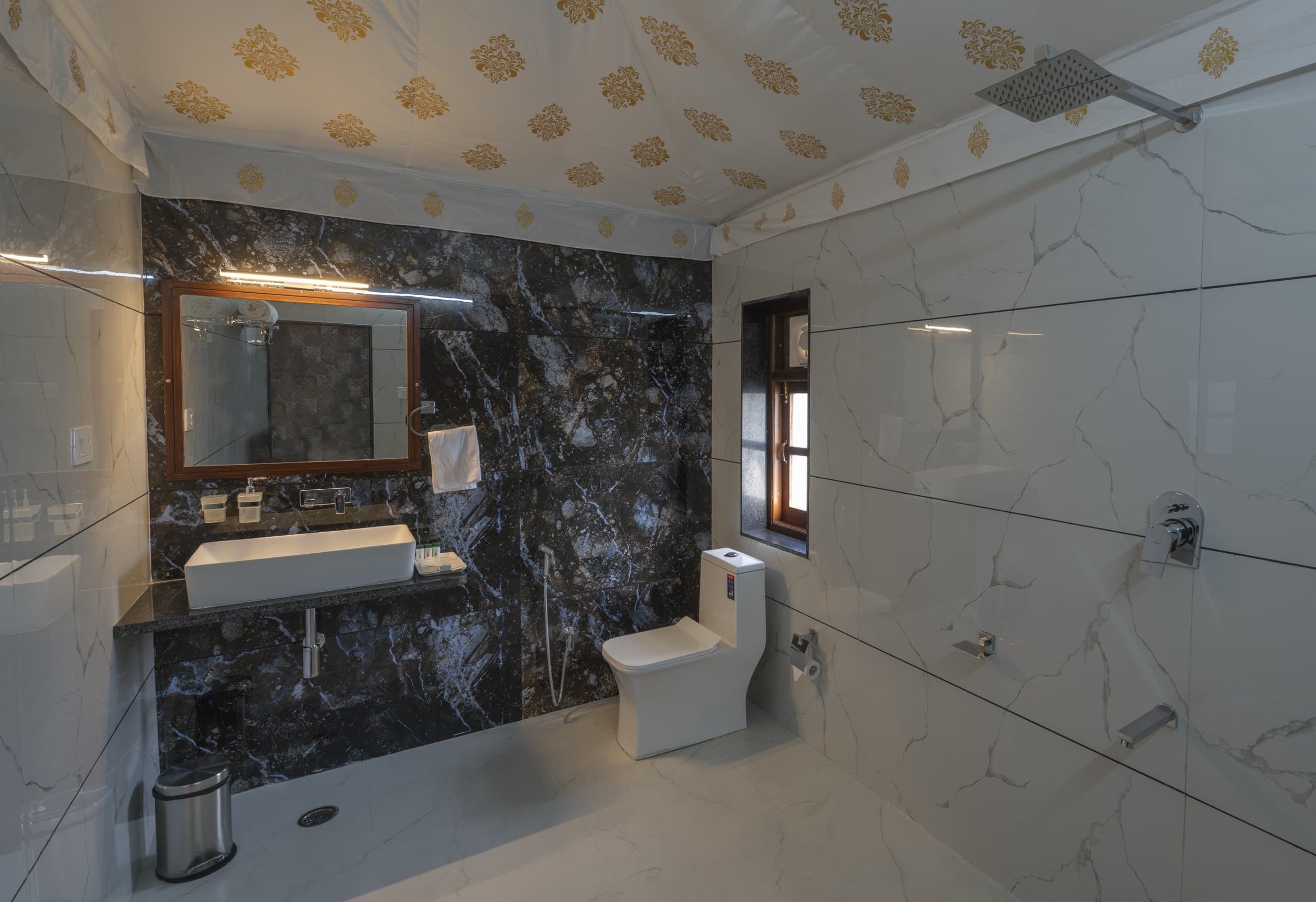 The private en-suite bathroom of a tented cottage, in marble and white tile