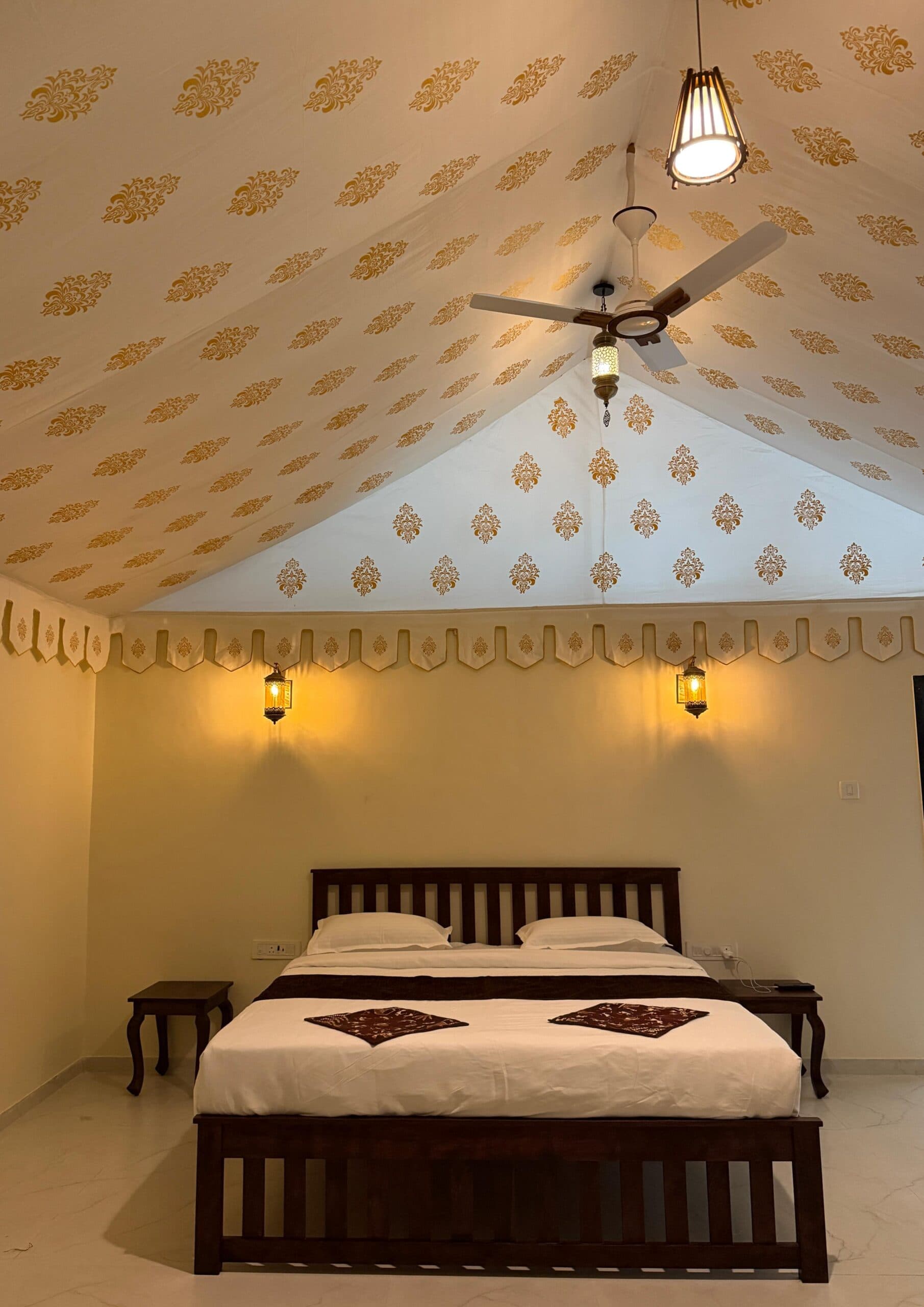 Inside a tented cottage: a made double bed under the printed canvas ceiling